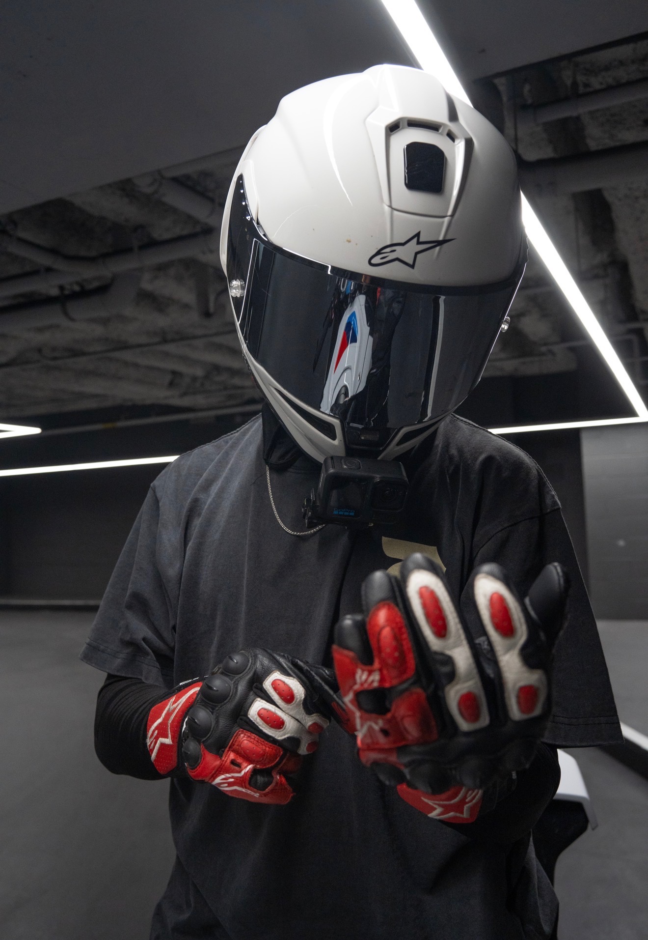 Blaze in Alpinestars gloves, fists together, helmet on, in a parking garage.