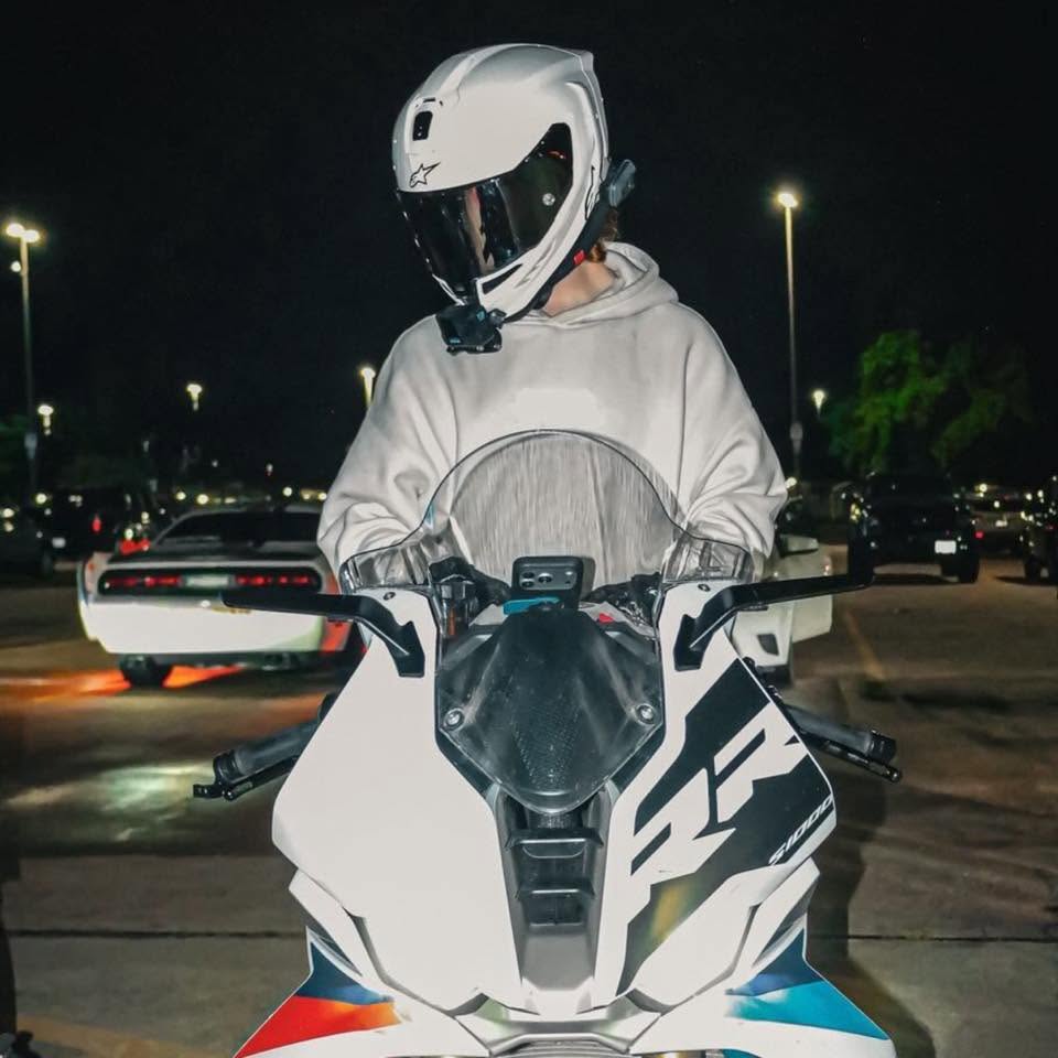 Blaze standing with his BMW S1000RR under a gas station canopy at night, Texaco pumps beside him.